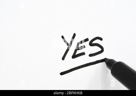 Close up view of a black fibre tip pen underlining the word "Yes" on white paper Stock Photo