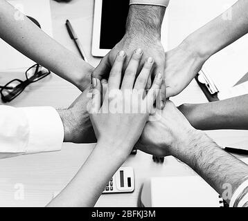 United hands of business team on workspace background top view.  Black and white retro stylization Stock Photo