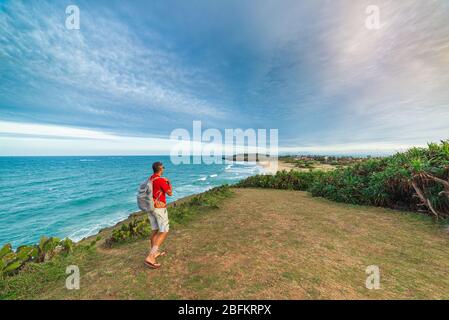 Man with backpack looking at tropical coast from cliff above. Vietnam travel destination, Phu Yen province between Da Nang and Nha Trang. Bai Xep gorg Stock Photo