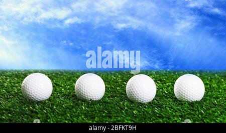 Golf balls on green grass against blue sky background Stock Photo