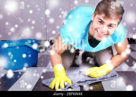 Young man cleaning floor in room over snow effect Stock Photo