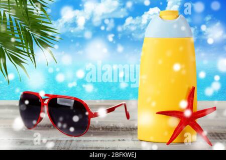 Bottle of suntan cream with sunglasses and sea star on table over snow effect Stock Photo