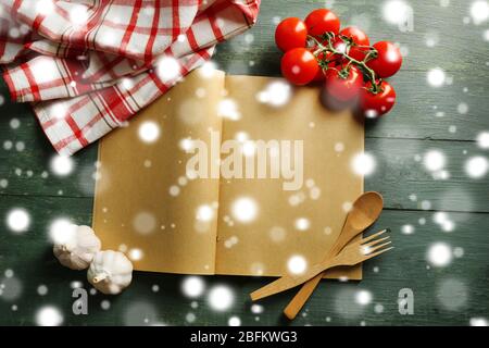 Open recipe book, vegetables and spices on wooden background over snow effect Stock Photo