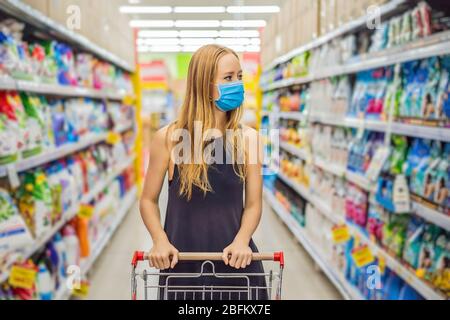 Alarmed female wears medical mask against coronavirus while grocery shopping in supermarket or store- health, safety and pandemic concept - young Stock Photo