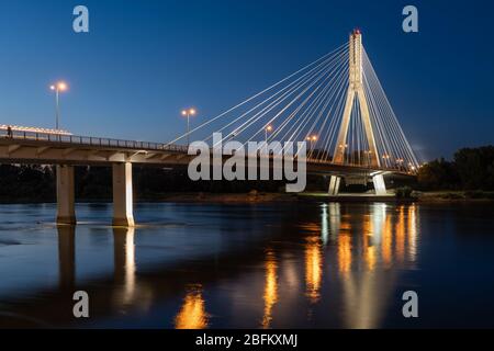 Warsaw, Poland - July 18, 2019: Swietokrzyski Bridge - Holy Cross Bridge over Vistula river illuminated at night, city landmark Stock Photo