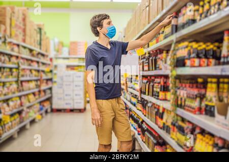 Alarmed man wears medical mask against coronavirus while grocery shopping in supermarket or store- health, safety and pandemic concept - young woman Stock Photo