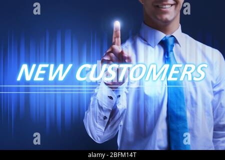 Businessman pressing new customers button on virtual screen. Internet and networking concept. Stock Photo