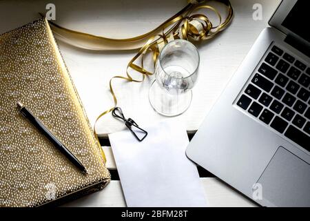 Wedding preparations with golden notebook, pen empty champagne glass, and binder clip on white envelope Stock Photo