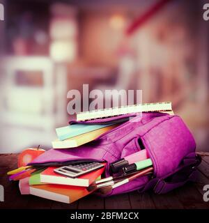 School backpack on wooden desk, on abstract background Stock Photo