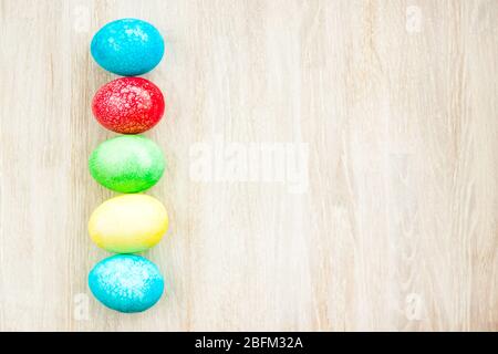 Colorful Easter egg side border on white wooden background flat lay Stock Photo