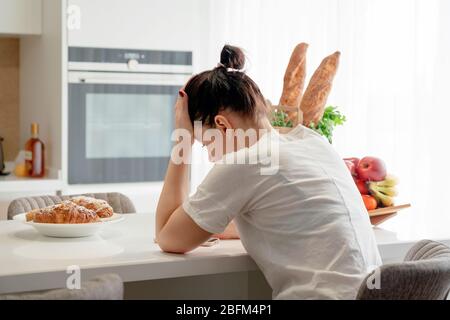 Young sad woman suffering in kitchen, Stressed housewife in kitchen Stock Photo