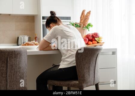 Young sad woman suffering in kitchen, Stressed housewife in kitchen Stock Photo