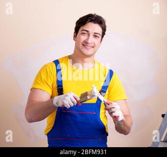 The young contractor employee applying plaster on wall Stock Photo