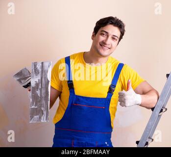 The young contractor employee applying plaster on wall Stock Photo