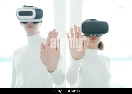 Palms of young male and female software developers in vr headsets keeping hands in front of camera while working in augmented realty Stock Photo