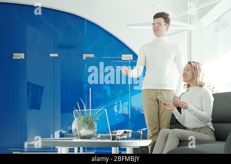 Two young successful software developers in smart glasses scanning information through transparent gadgets and looking at display Stock Photo