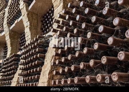 Wine bottles covered with spider web stacked up in old wine cellar  Stock Photo