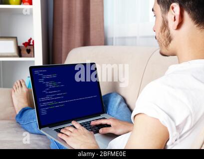 Man using laptop, writing programming code on laptop Stock Photo