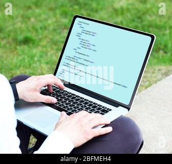 Man using laptop, writing programming code on laptop Stock Photo