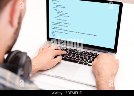 Man using laptop, writing programming code on laptop Stock Photo