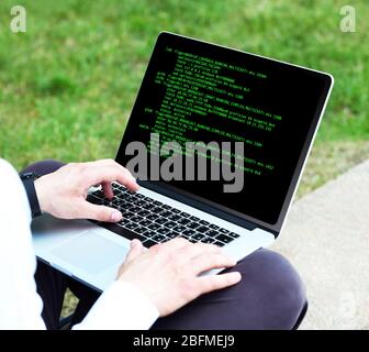 Man using laptop, writing programming code on laptop Stock Photo