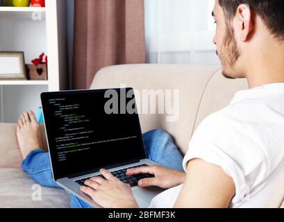 Man using laptop, writing programming code on laptop Stock Photo