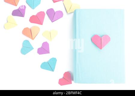 Book and origami hearts on light background Stock Photo