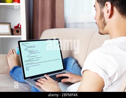 Man using laptop, writing programming code on laptop Stock Photo