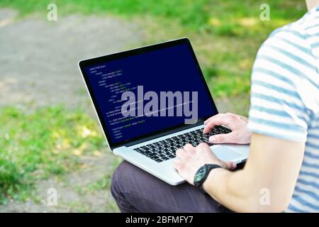 Man using laptop, writing programming code on laptop Stock Photo