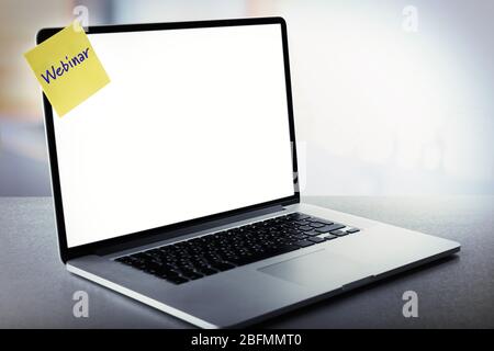Webinar written on sticky note on laptop screen Stock Photo
