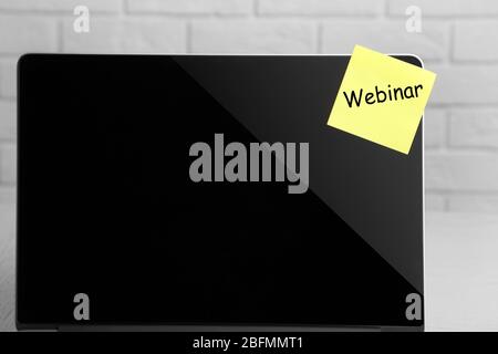 Webinar written on sticky note on laptop screen Stock Photo