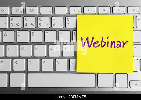 Webinar written on sticky note on laptop keyboard Stock Photo