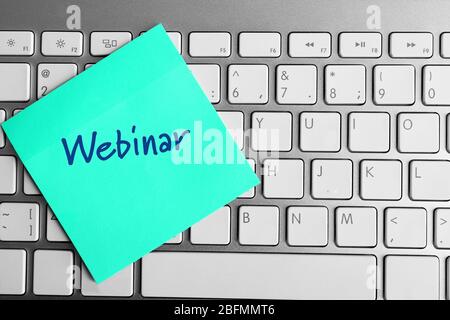 Webinar written on sticky note on laptop keyboard Stock Photo