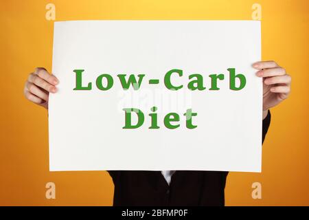 Woman holding paper with Low-Carb Diet text on color background Stock Photo