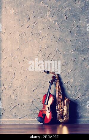 Violin and saxophone on gray wall background Stock Photo