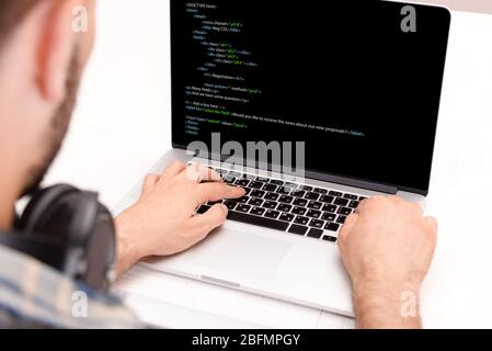 Man using laptop, writing programming code on laptop Stock Photo