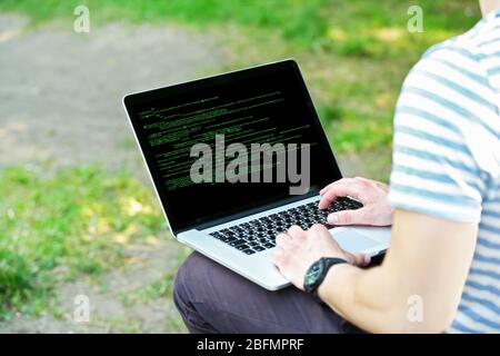 Man using laptop, writing programming code on laptop Stock Photo