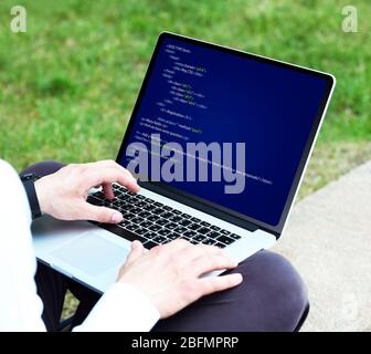 Man using laptop, writing programming code on laptop Stock Photo