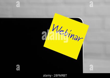 Webinar written on sticky note on laptop screen Stock Photo