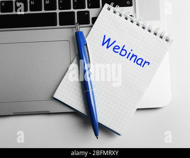 Webinar written in notebook, laptop and pen on table, top view Stock Photo