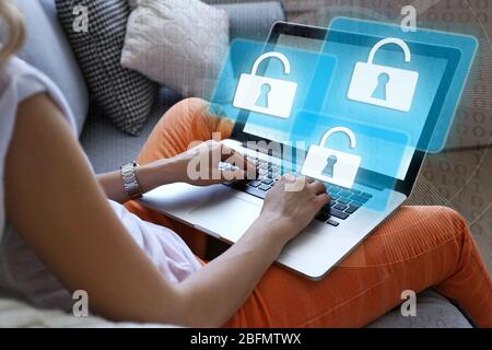 Woman working on laptop with icons security on virtual display. Technology, internet and networking concept. Stock Photo