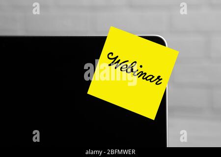 Webinar written on sticky note on laptop screen Stock Photo
