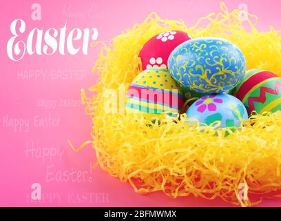 Easter greeting card. Multicoloured eggs in straw on pink background Stock Photo