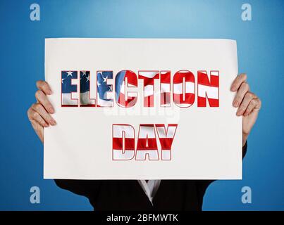 Woman holding paper with Election Day text on blue background Stock Photo