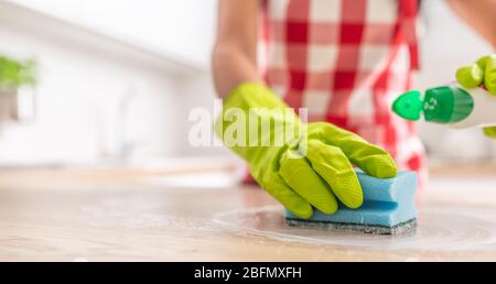 Detail of a hand in a rubber glove and blue sponge cleaning a surface with a detergent. Stock Photo