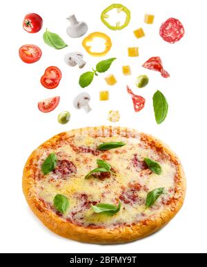 Tasty pizza with falling vegetables and pieces of salami, isolated on white Stock Photo