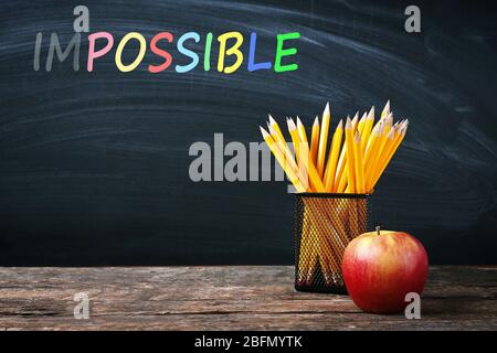 Word impossible transformed into possible on blackboard and school supplies Stock Photo