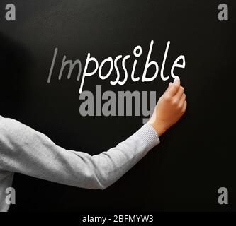 Hand writing word impossible transformed into possible  on blackboard Stock Photo