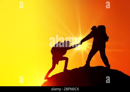 Helping hands with sunlight between two climbers Stock Photo