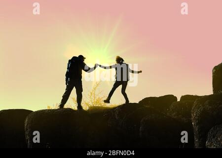 Helping hands with sunlight between two climbers Stock Photo